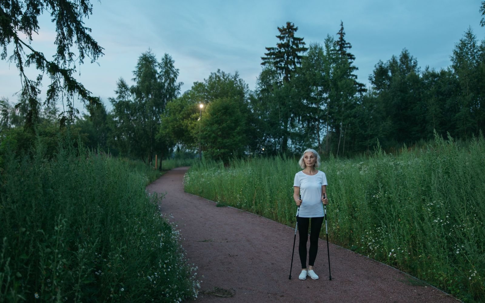 Personne pratiquant la marche nordique sur un chemin de parc