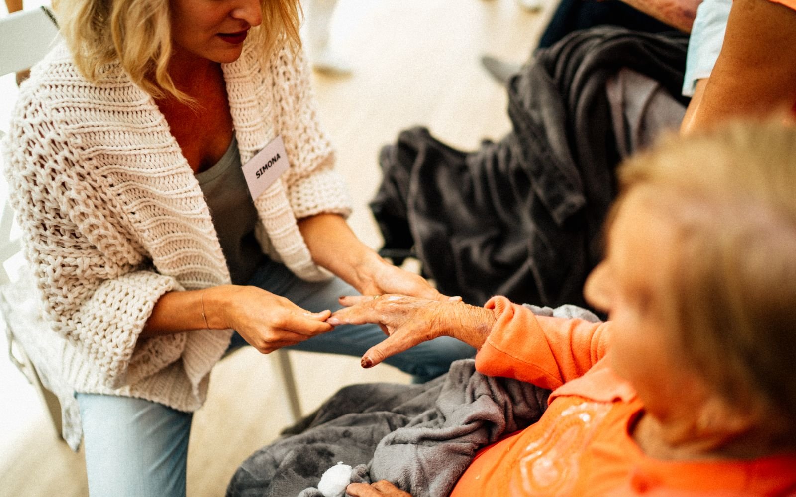Personne accompagnant une femme âgée assise dans son intérieur